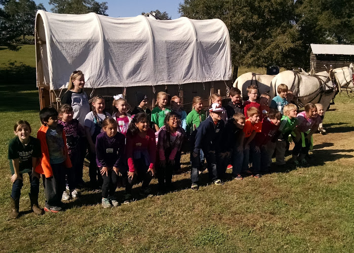 school group in front of covered wagob